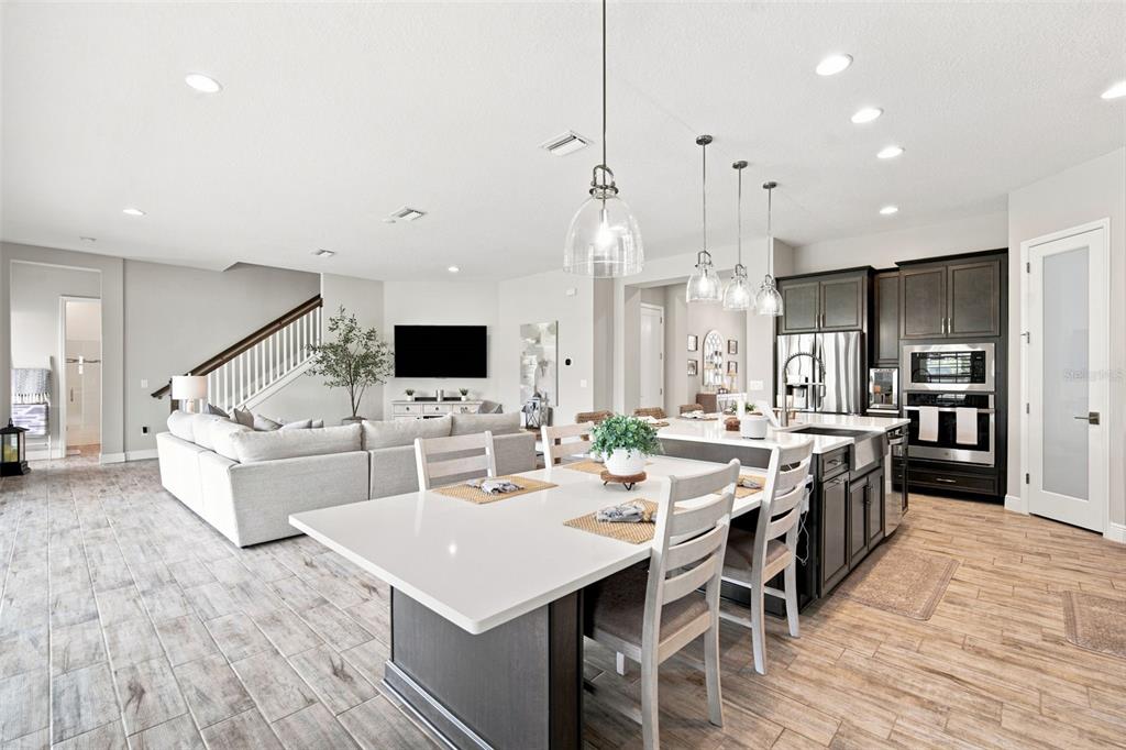 An open-concept kitchen and living area features a large island, dark cabinetry, and wood-look flooring — 4587 SHORELEAF LOOP, VALRICO, FL