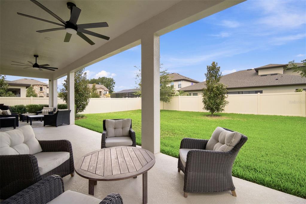 A covered patio with outdoor furniture overlooks a fenced backyard with a green lawn — 4587 SHORELEAF LOOP, VALRICO, FL