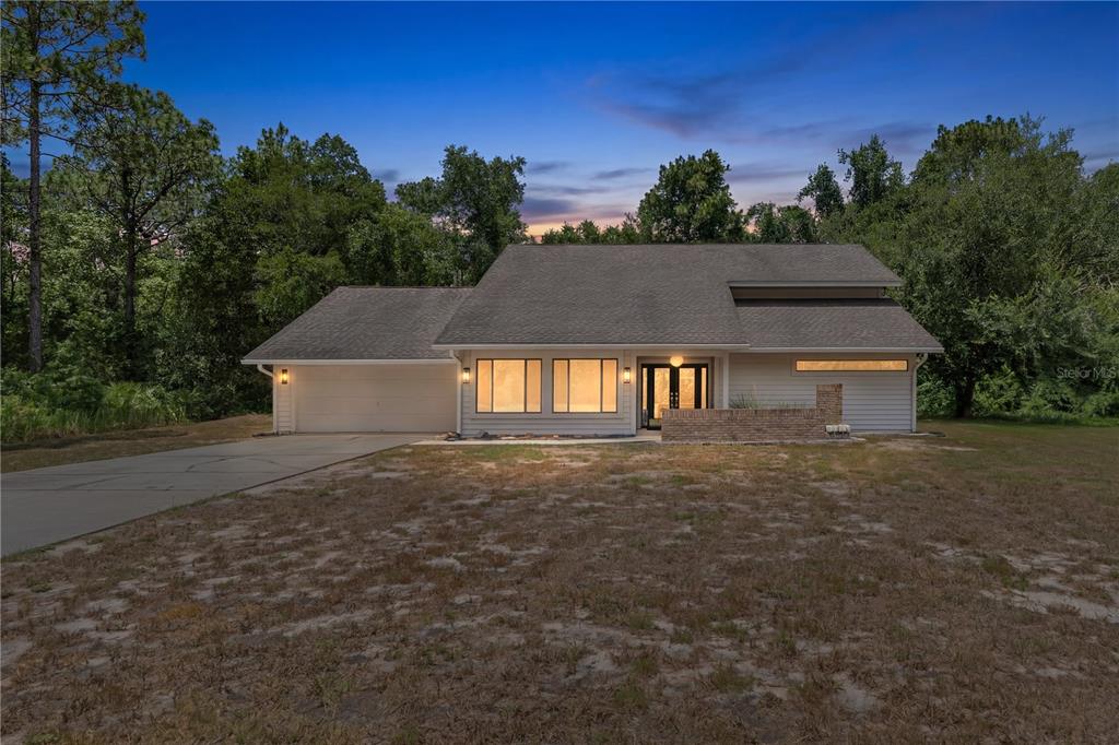 A single-story house with a garage, large windows, and a brick wall at the entrance — 10 SYCAMORE COURT S, HOMOSASSA, FL