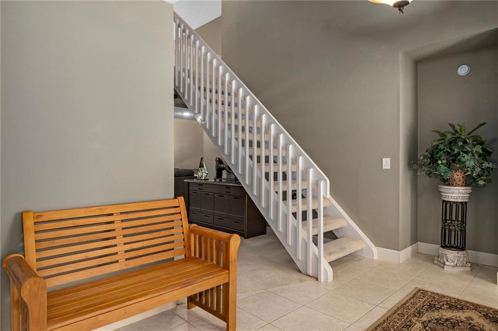 A wooden bench sits in a tiled entryway next to a staircase with white railings — 10 SYCAMORE COURT S, HOMOSASSA, FL