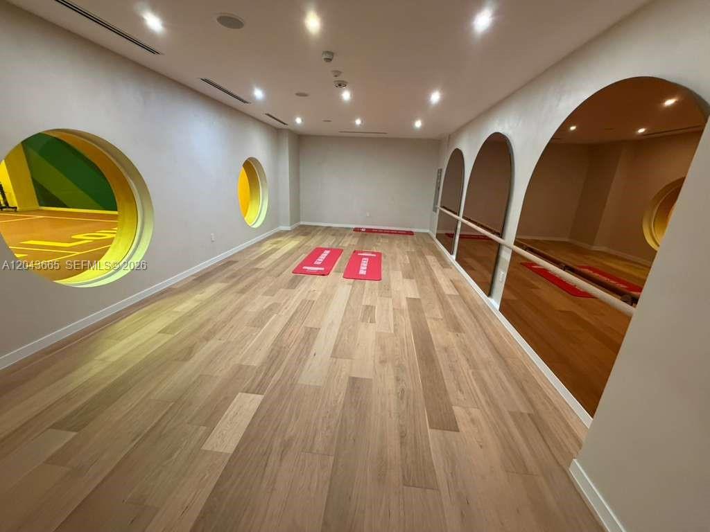 A yoga or fitness room features light wood flooring, arched mirrors, and circular wall cutouts — 3100 1st # 515, Miami FL 33137, MIAMI, FL
