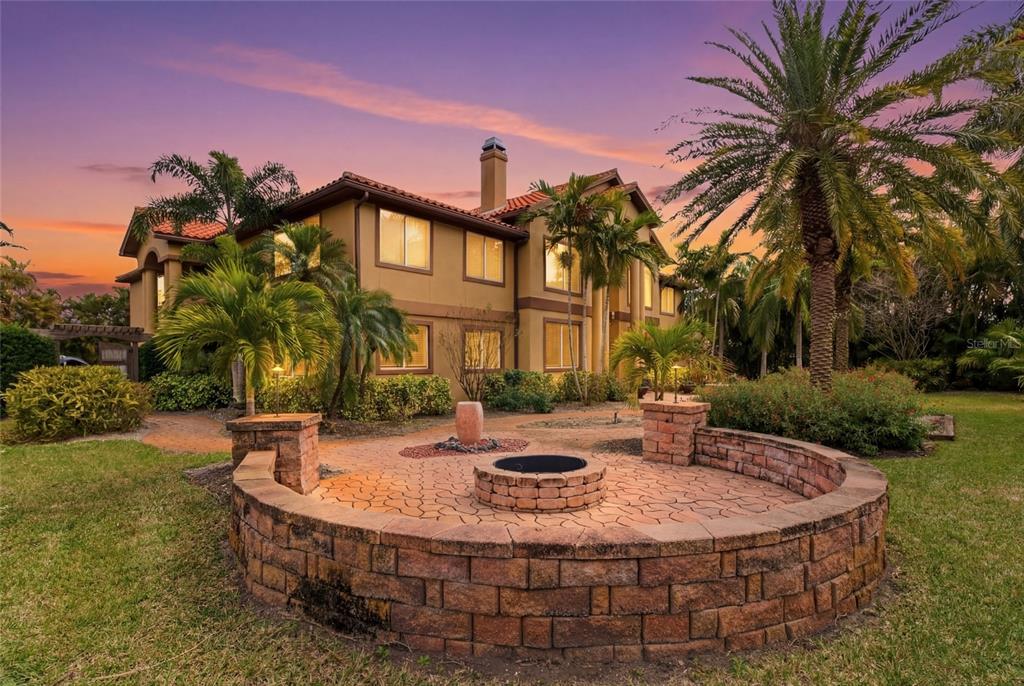 A two-story house with a stone fire pit and patio in the front yard — 303 SUNNY LANE, BELLEAIR, FL