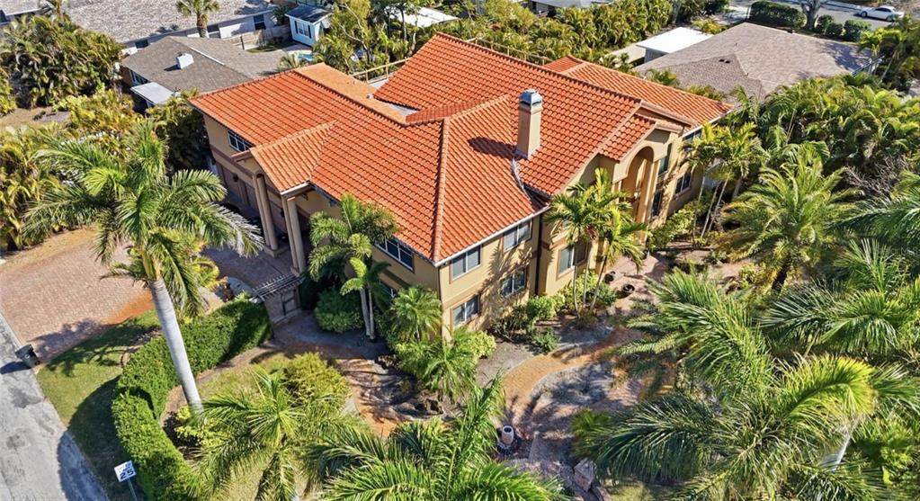 An aerial view shows a two-story house with a red tile roof and palm trees — 303 SUNNY LANE, BELLEAIR, FL