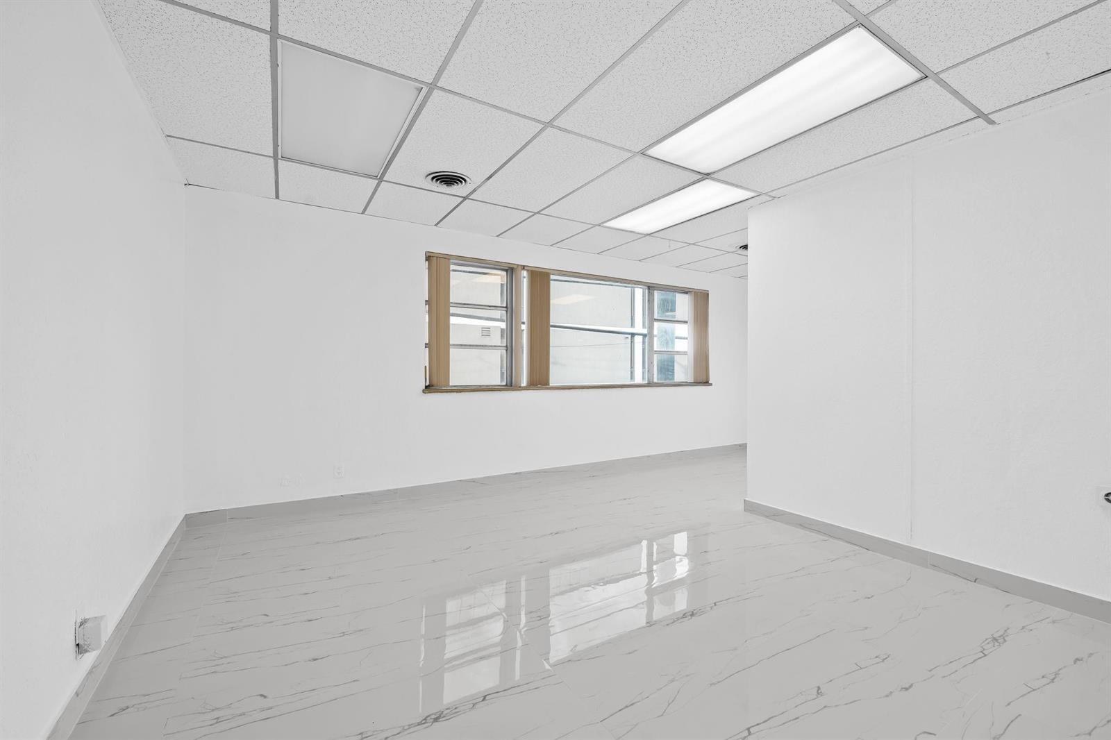 An empty office room features white walls, a drop ceiling, and light-colored marble-patterned tile flooring — 2601 E Atlantic Boulevard, Pompano Beach FL 33062, POMPANO BEACH, FL