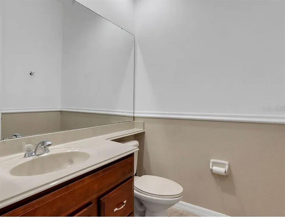 A bathroom features a wooden vanity with a sink, a large mirror, and a toilet — 2286 CHATHAM PLACE DRIVE, ORLANDO, FL