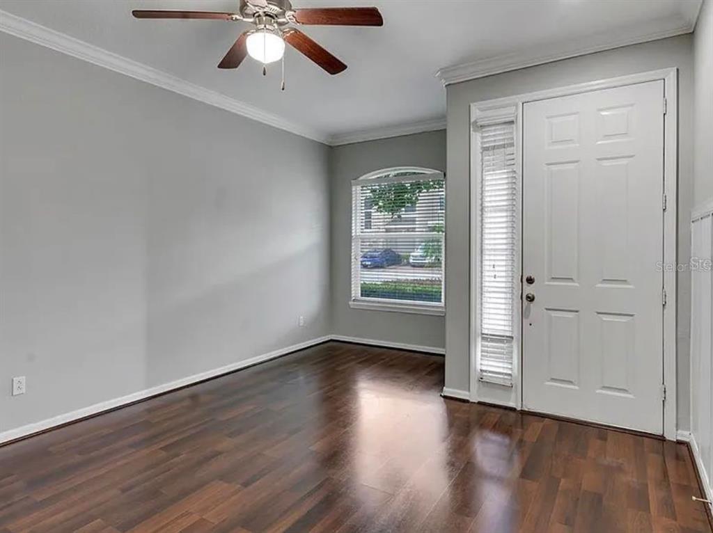 An empty room with gray walls, dark wood flooring, a ceiling fan, and a front door — 2286 CHATHAM PLACE DRIVE, ORLANDO, FL