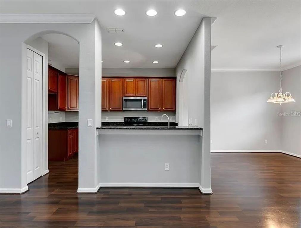 A kitchen with dark wood cabinets and granite countertops overlooks a dining area with wood floors — 2286 CHATHAM PLACE DRIVE, ORLANDO, FL