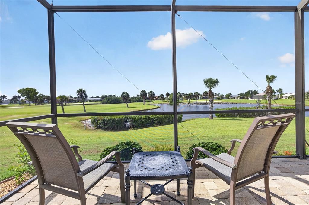 A screened-in patio features two chairs and a small table overlooking a golf course pond — 2107 PADRE ISLAND DRIVE, PUNTA GORDA, FL