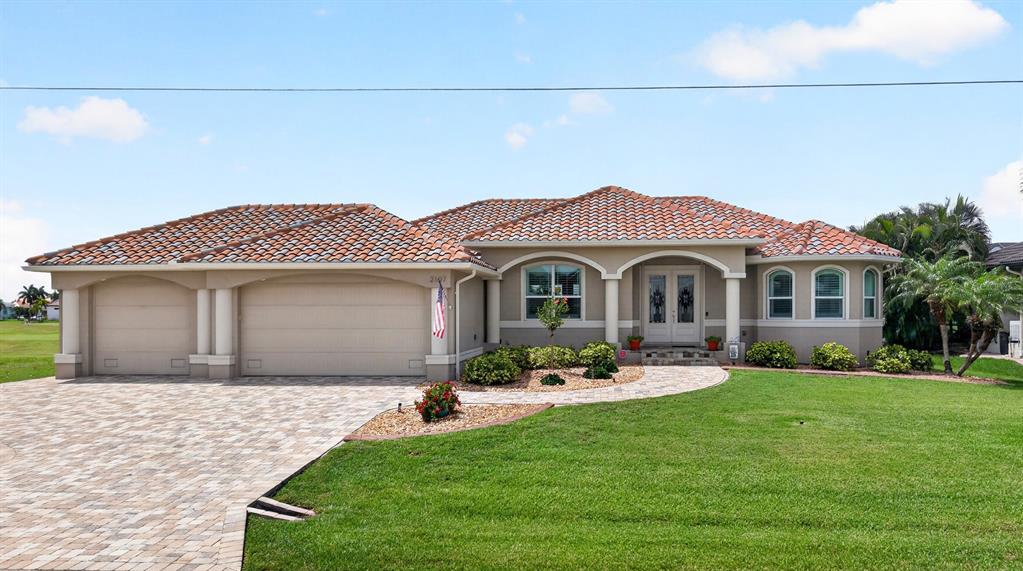 A single-story house with a tiled roof, beige stucco exterior, and a paved driveway — 2107 PADRE ISLAND DRIVE, PUNTA GORDA, FL