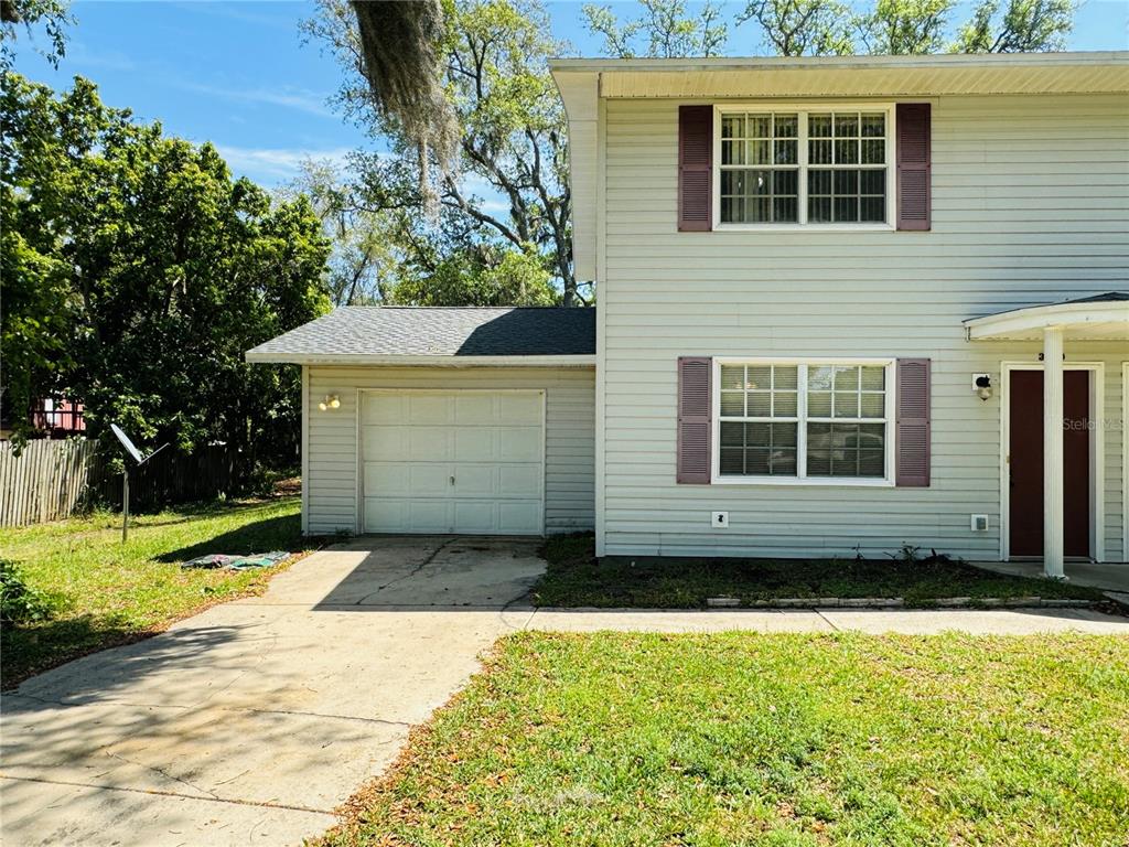 A two-story house with light siding, a single-car garage, and a concrete driveway — 3818 RED OAK COURT, LAKE WALES, FL