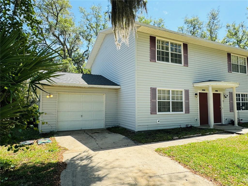 A two-story duplex with light siding, a single-car garage, and a shared front entrance — 3818 RED OAK COURT, LAKE WALES, FL