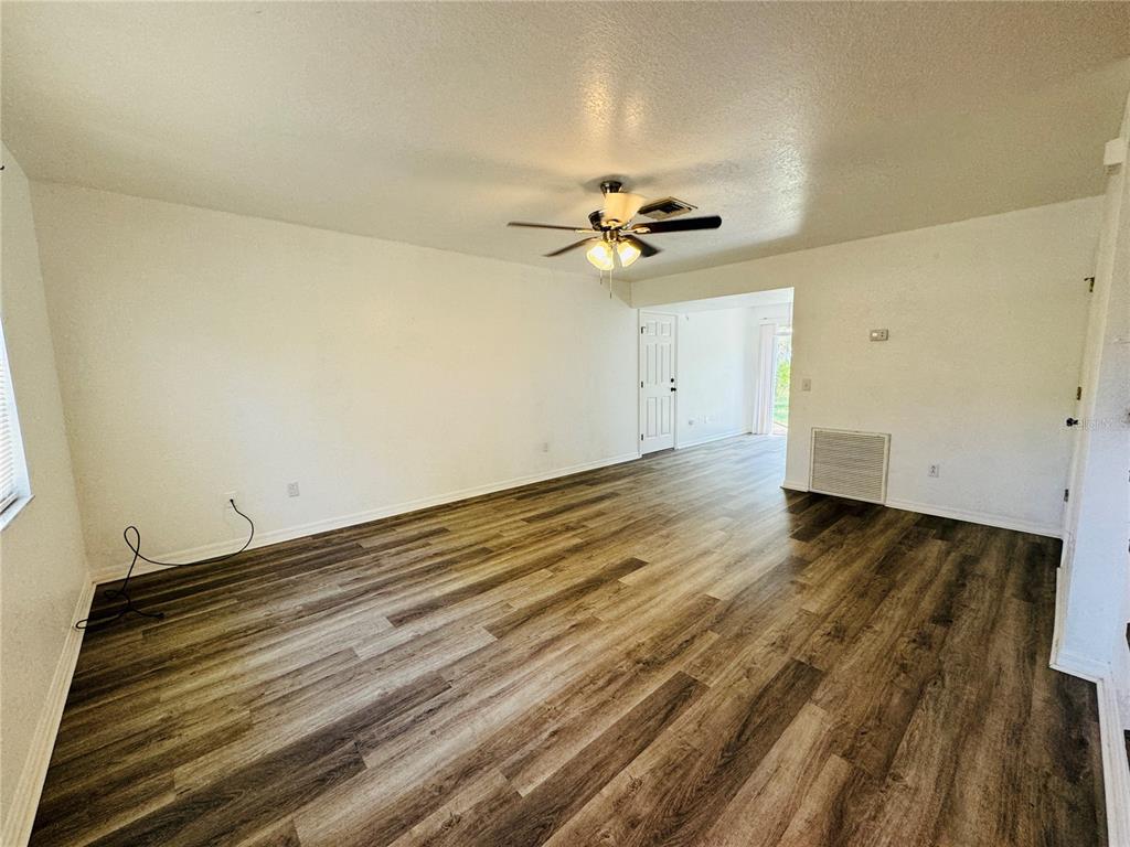 A spacious living room features white walls, wood-look flooring, and a ceiling fan — 3818 RED OAK COURT, LAKE WALES, FL