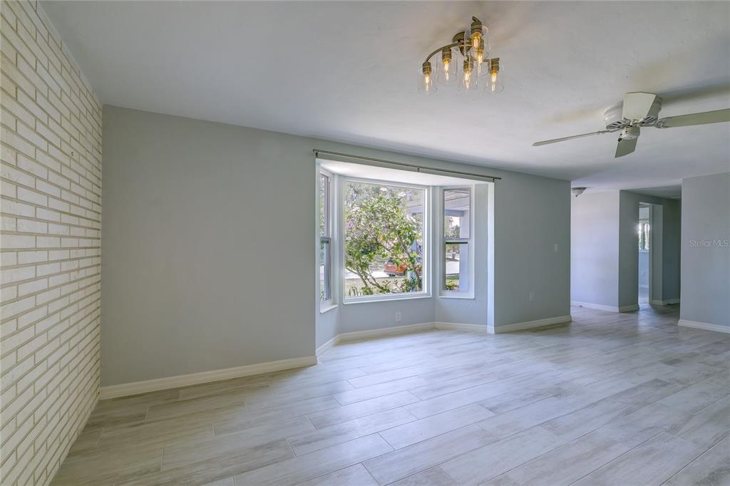 A living room features light gray walls, wood-look tile flooring, and a white brick wall — 3024 CHASE CIRCLE, SARASOTA, FL