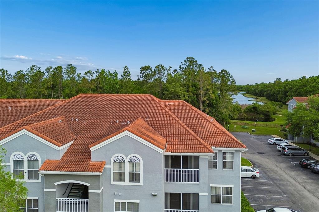 An aerial view of a multi-story apartment building with a red tile roof and parking — 18001 RICHMOND PLACE DRIVE UNIT 1030, TAMPA, FL