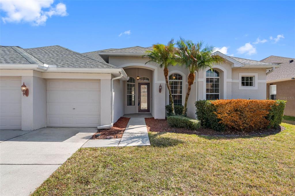 The exterior of a single-story house features a garage, a front entrance, and palm trees — 4820 PORTMARNOCK WAY, WESLEY CHAPEL, FL