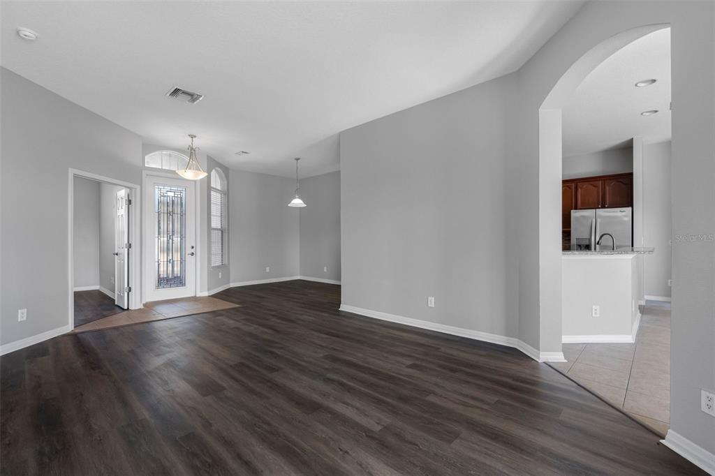 An interior view of a living area with dark wood flooring, gray walls, and an entryway — 4820 PORTMARNOCK WAY, WESLEY CHAPEL, FL