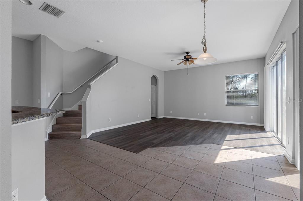An open-concept living area features tile flooring, a dark wood-look section, and a staircase — 4820 PORTMARNOCK WAY, WESLEY CHAPEL, FL