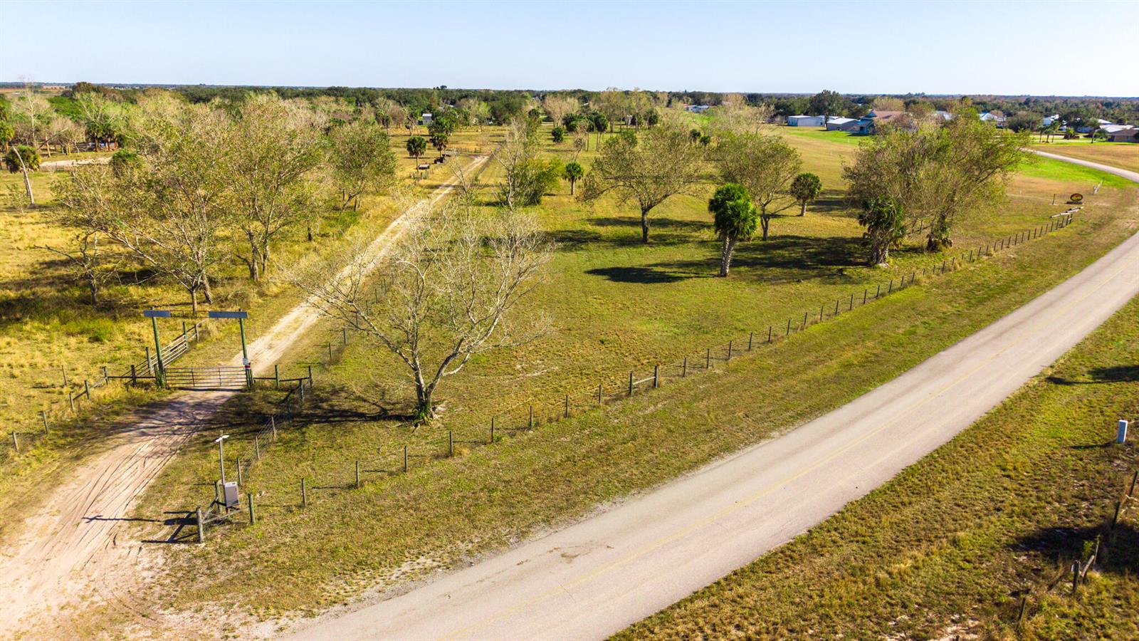 An aerial view shows a rural property with a gated entrance, dirt driveway, and trees — 0 SW 144th Parkway, Okeechobee FL 34974, OKEECHOBEE, FL