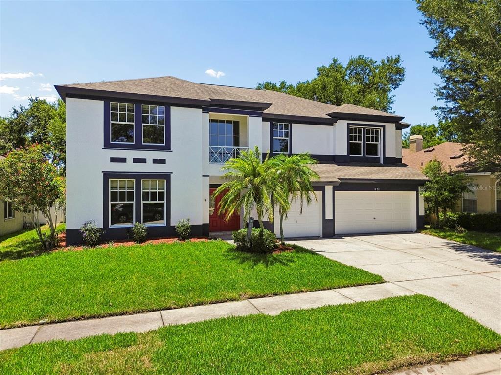 A two-story house with white stucco walls, dark trim, and a three-car garage — 1828 LONGVIEW LANE, TARPON SPRINGS, FL