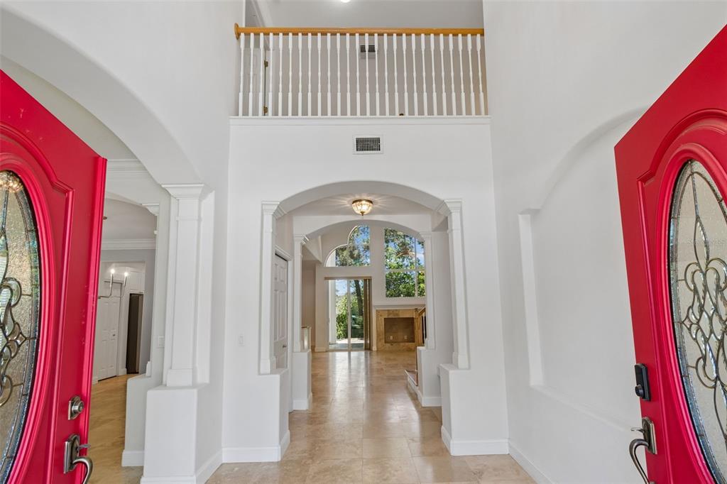 A bright entryway features a high ceiling, tile flooring, and two vibrant red front doors — 1828 LONGVIEW LANE, TARPON SPRINGS, FL