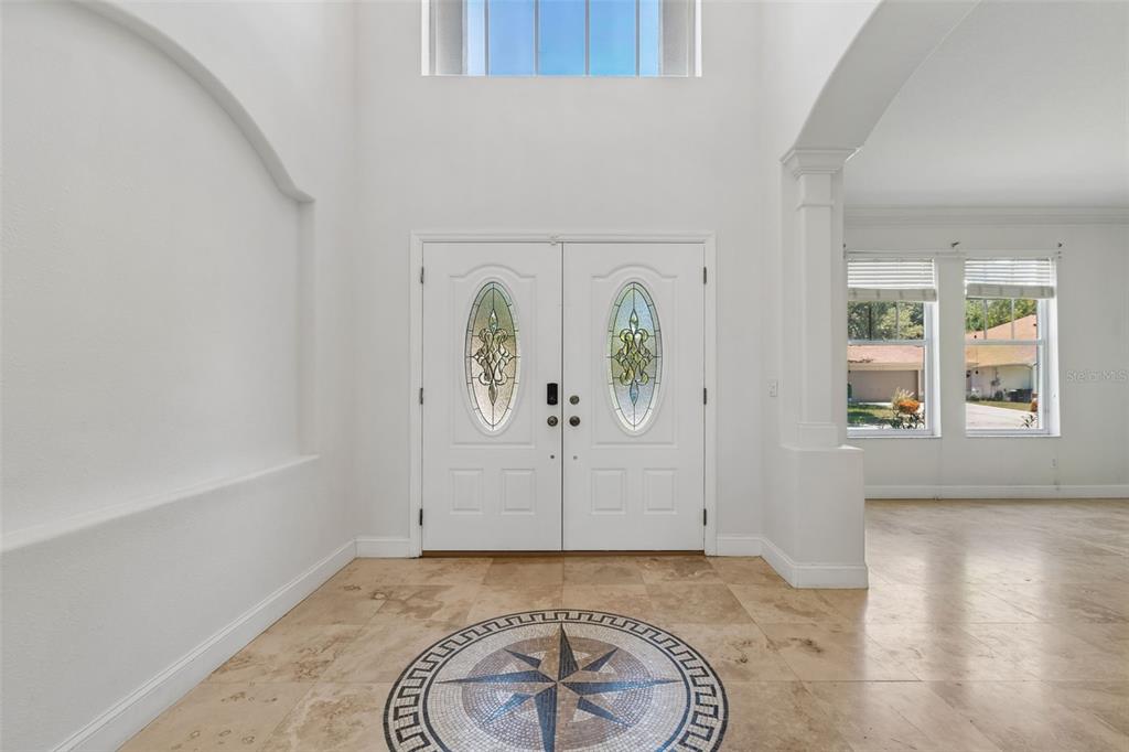 A bright foyer features a compass rose tile inlay, double front doors, and high ceilings — 1828 LONGVIEW LANE, TARPON SPRINGS, FL