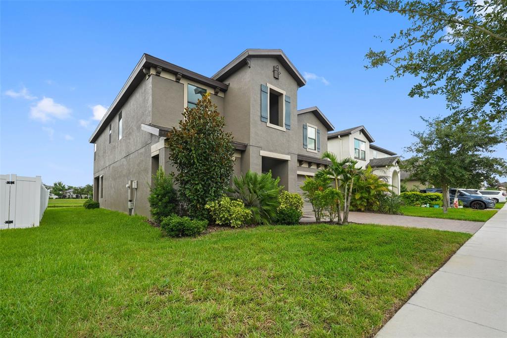A two-story gray stucco house with a paved driveway and a manicured front lawn — 13134 MONACH ISLES DRIVE, RIVERVIEW, FL