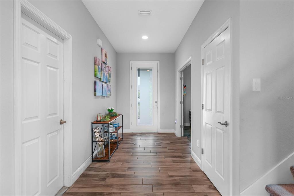A bright entryway features wood-look tile flooring, white doors, and a glass-paneled front door — 13134 MONACH ISLES DRIVE, RIVERVIEW, FL