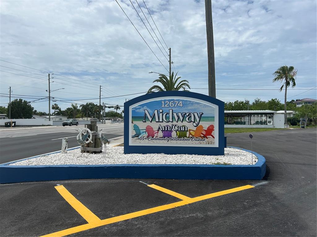A blue sign for a 55+ community stands in a gravel bed by a road — 12674 SEMINOLE BOULEVARD UNIT S18, LARGO, FL