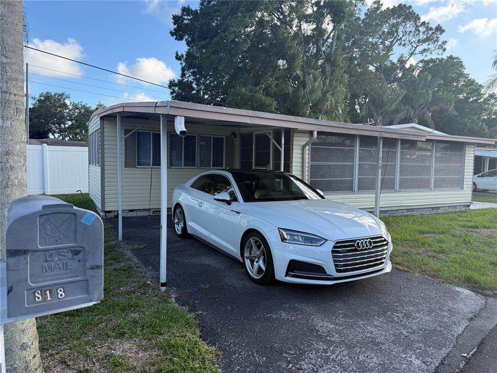 A white Audi coupe is parked under a carport attached to a light-colored mobile home — 12674 SEMINOLE BOULEVARD UNIT S18, LARGO, FL