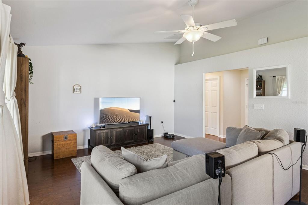 A living room features a sectional sofa, a television on a wooden console, and hardwood floors — 1920 COUNTRY MANOR STREET, BARTOW, FL