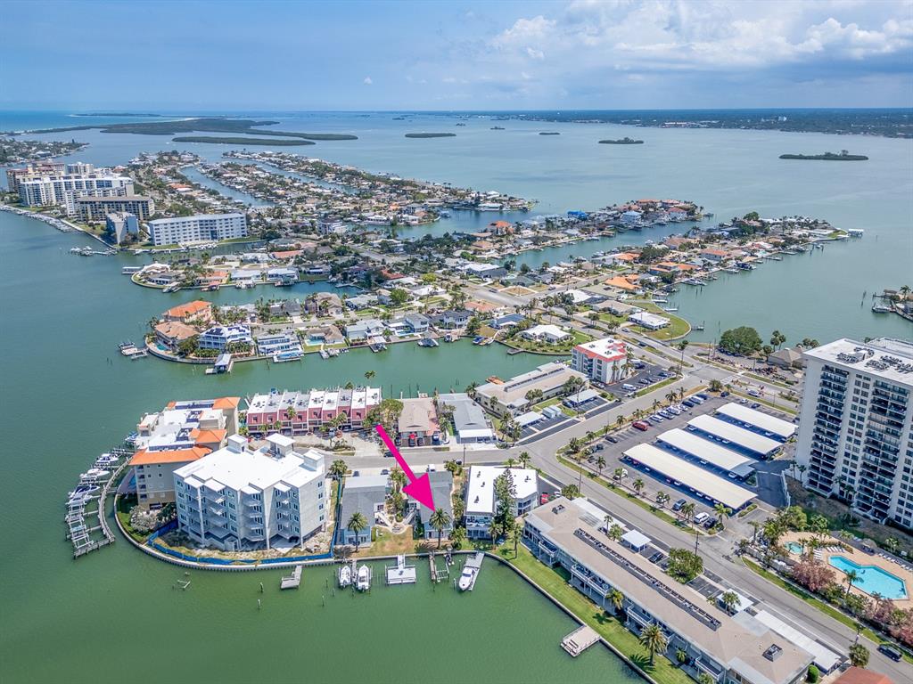 An aerial view shows a waterfront residential property marked with a pink arrow — 241 SKIFF POINT UNIT 4, CLEARWATER BEACH, FL