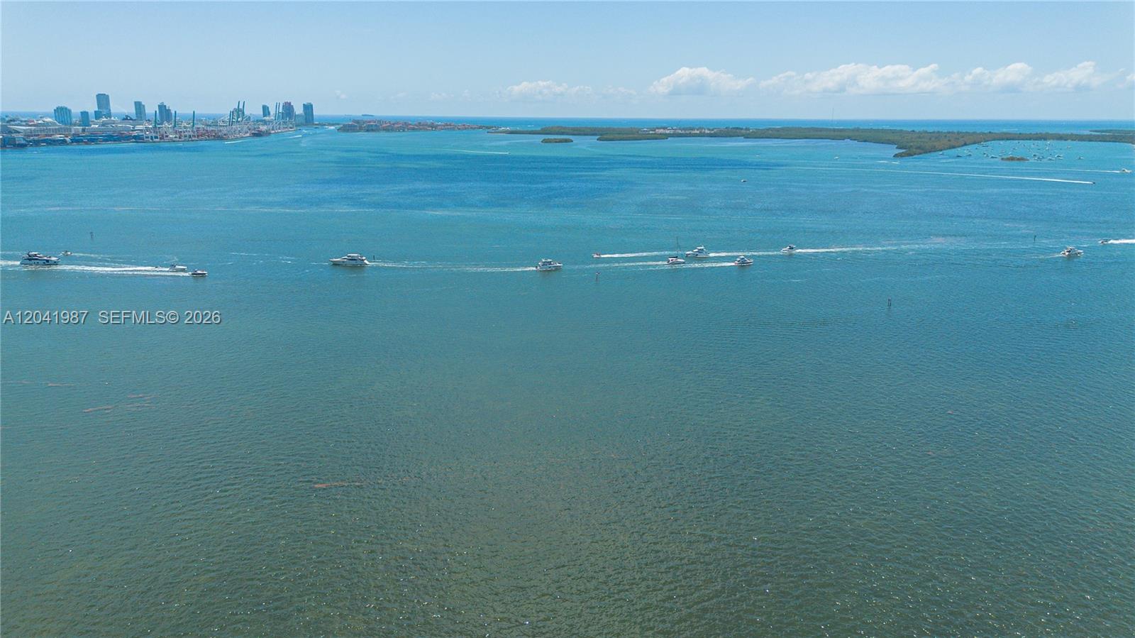 An aerial view shows multiple boats traveling across a large body of water near a city — 1200 Brickell Bay Dr # 4121, Miami FL 33131, MIAMI, FL