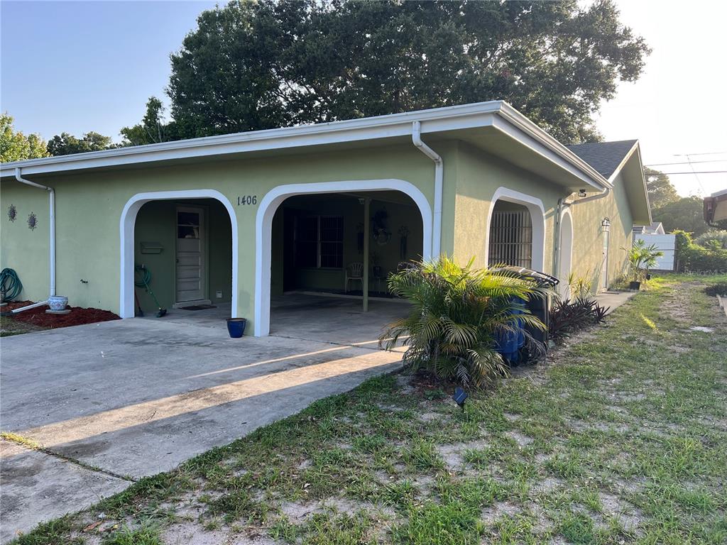 A single-story house with a green exterior, a covered carport, and a concrete driveway — 1406 N SATURN AVENUE, CLEARWATER, FL