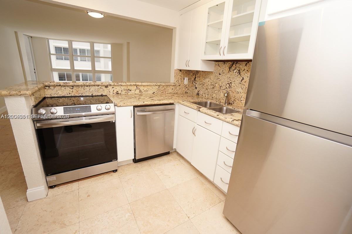 A kitchen features stainless steel appliances, white cabinets, and granite countertops — 1228 West Ave # 513, Miami Beach FL 33139, MIAMI BEACH, FL
