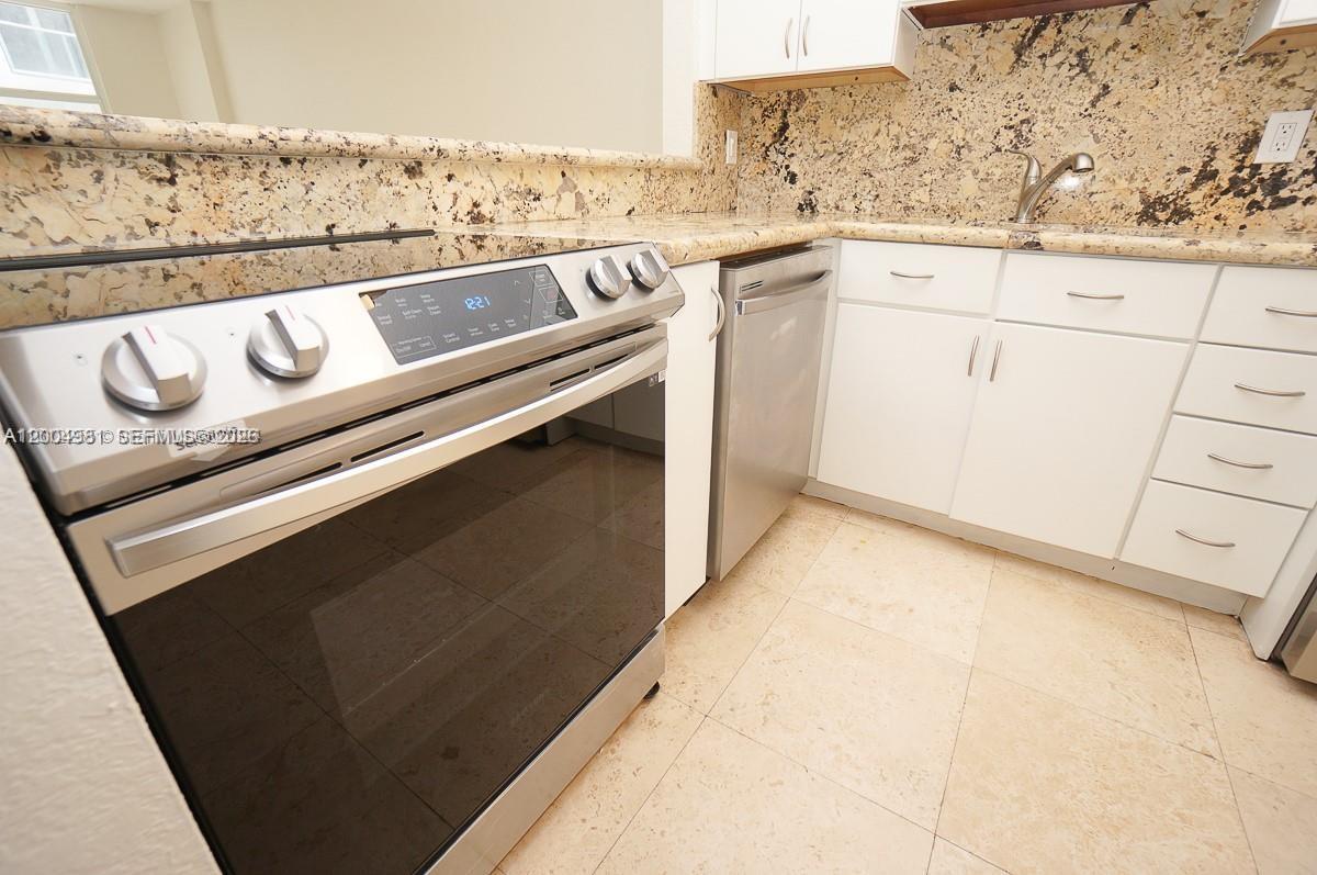 A kitchen features stainless steel appliances, white cabinets, and speckled granite countertops — 1228 West Ave # 513, Miami Beach FL 33139, MIAMI BEACH, FL