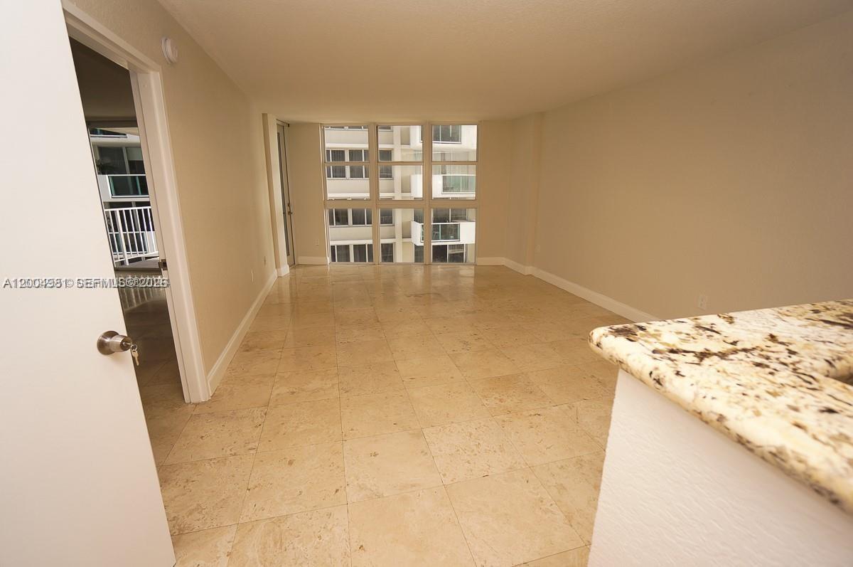 An empty room features light-colored tile flooring, white walls, and a large window grid — 1228 West Ave # 513, Miami Beach FL 33139, MIAMI BEACH, FL