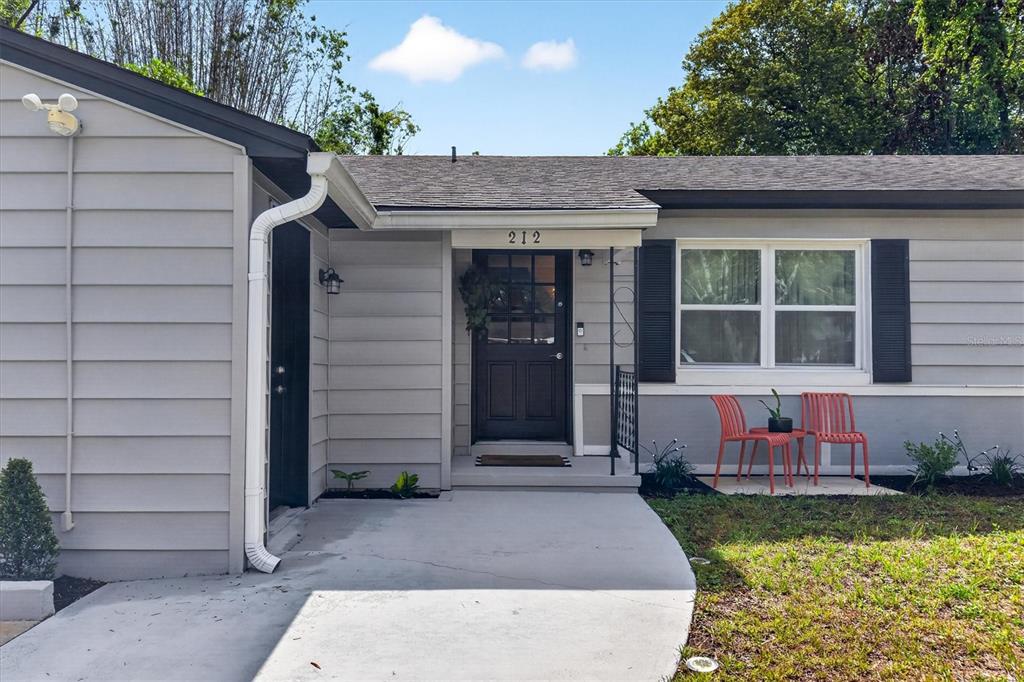 A gray house exterior features a black front door, a concrete walkway, and two chairs — 212 S GLENWOOD AVENUE, ORLANDO, FL