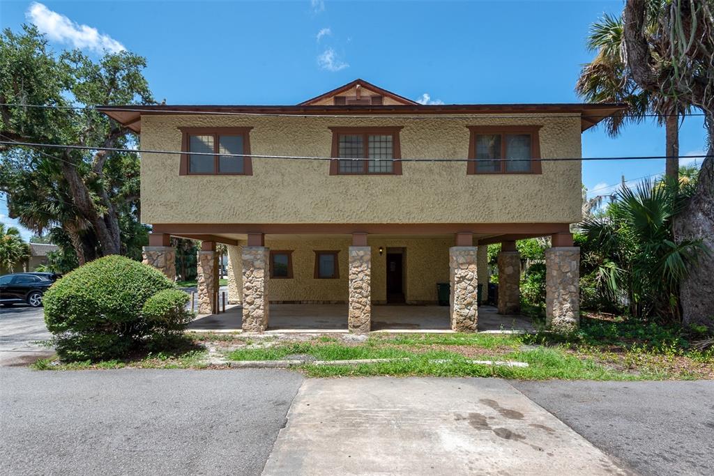 A two-story building with a raised upper level supported by stone-clad columns and a carport — 205 MAGNOLIA STREET, NEW SMYRNA BEACH, FL