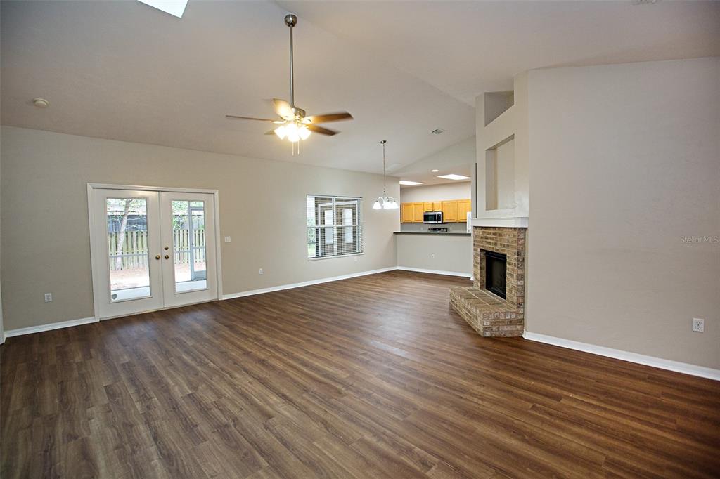 A spacious living room features wood-look flooring, a brick fireplace, and an open kitchen — 4314 NW 35TH STREET, GAINESVILLE, FL