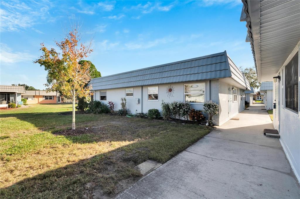 A single-story residential building with a gray mansard roof and a concrete walkway — 202 BEDFORD TRAIL UNIT 112, SUN CITY CENTER, FL