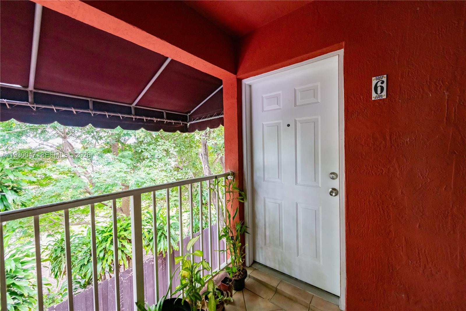 A white door with the number six sits on a balcony with red walls — 63 NW 17th Pl # 6, Miami FL 33125, MIAMI, FL