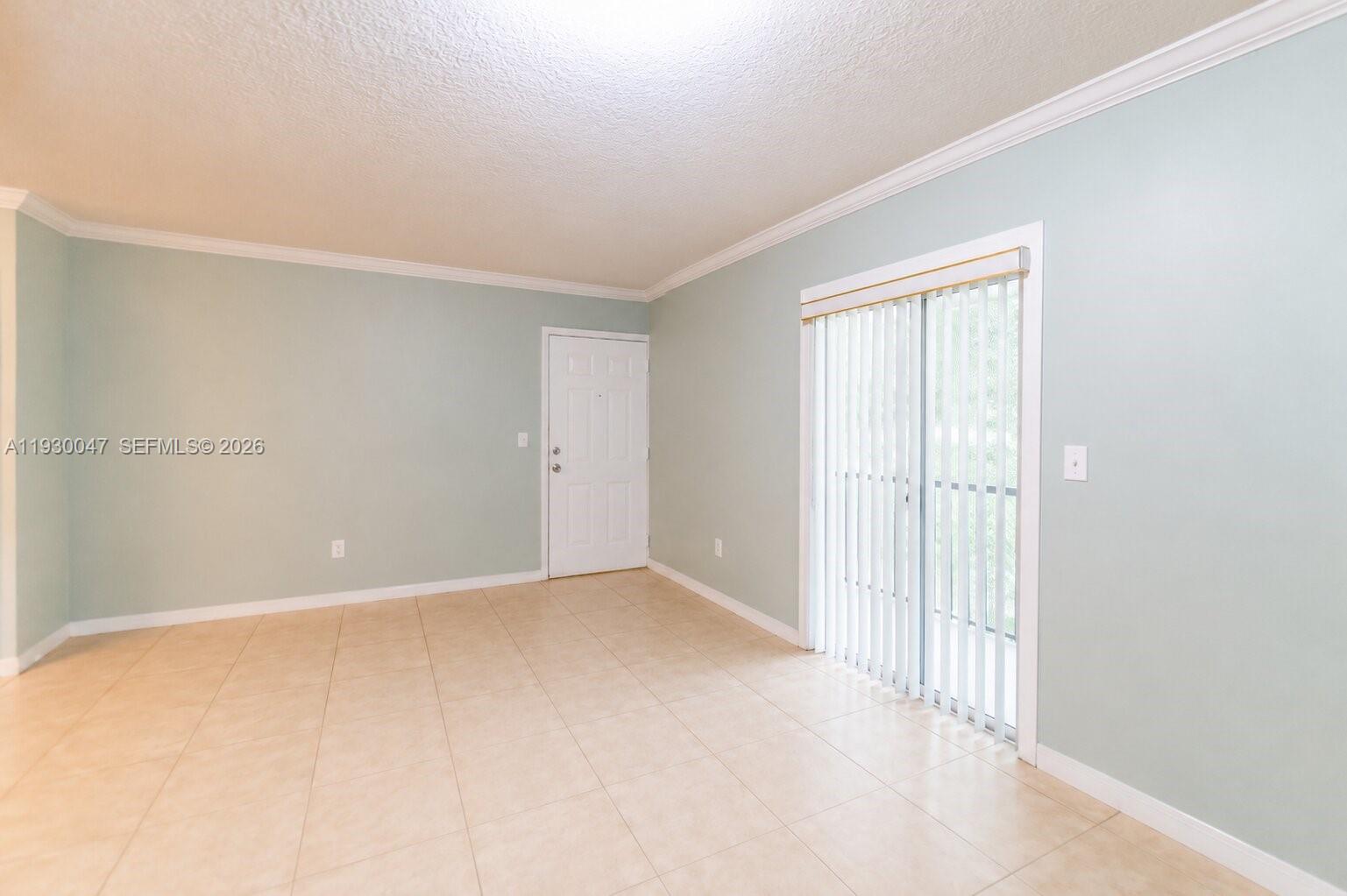 An empty room features light blue walls, beige tile flooring, and a sliding glass door — 63 NW 17th Pl # 6, Miami FL 33125, MIAMI, FL