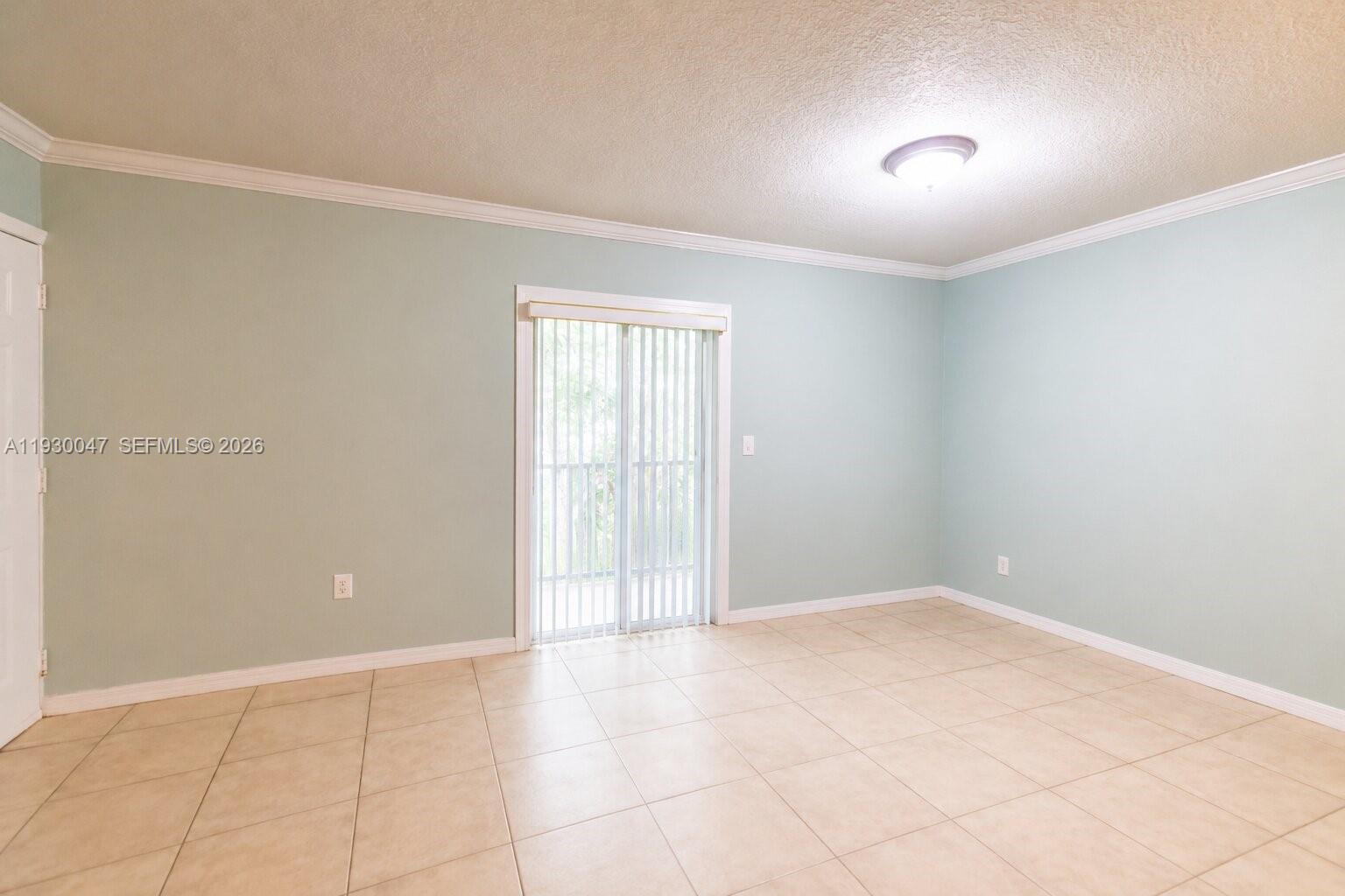 A room with light green walls, tile flooring, and a sliding glass door — 63 NW 17th Pl # 6, Miami FL 33125, MIAMI, FL