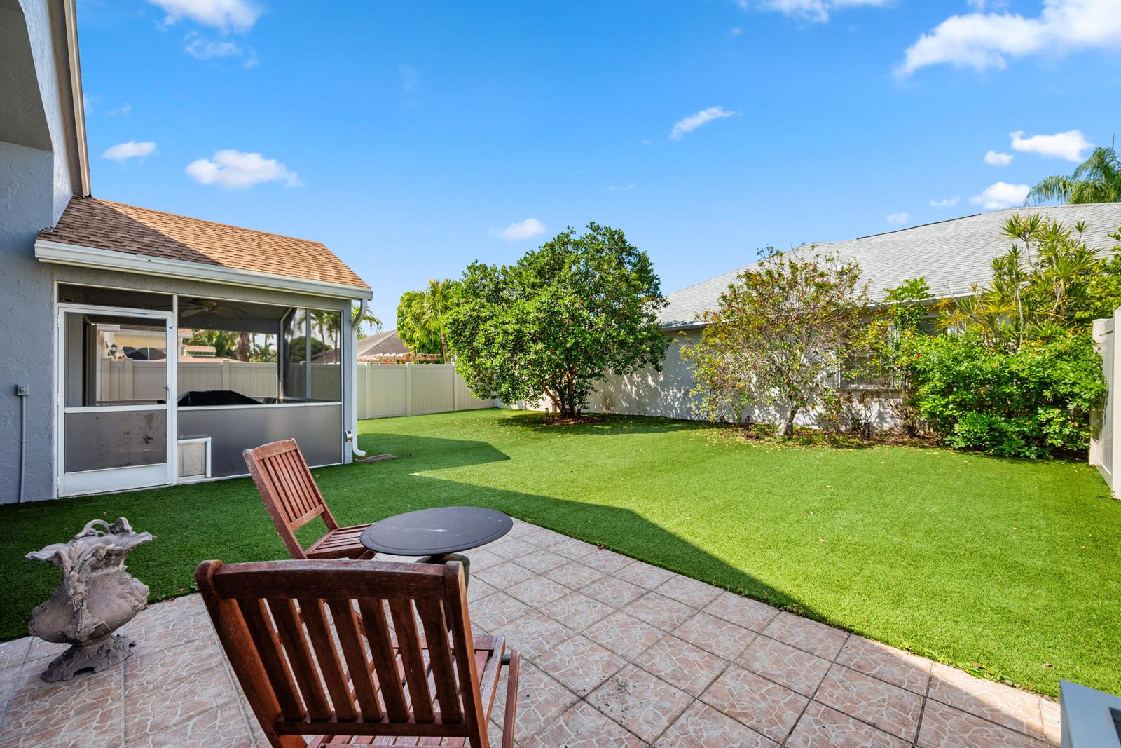 A backyard patio with wooden chairs, a small table, and artificial turf lawn — 1097 Aviary Road, Wellington FL 33414, WELLINGTON, FL