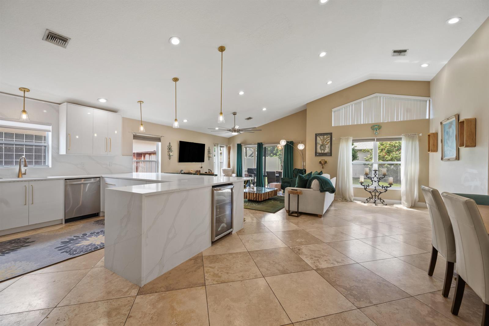 An open-concept kitchen and living area features white cabinetry, marble countertops, and tile flooring — 1097 Aviary Road, Wellington FL 33414, WELLINGTON, FL