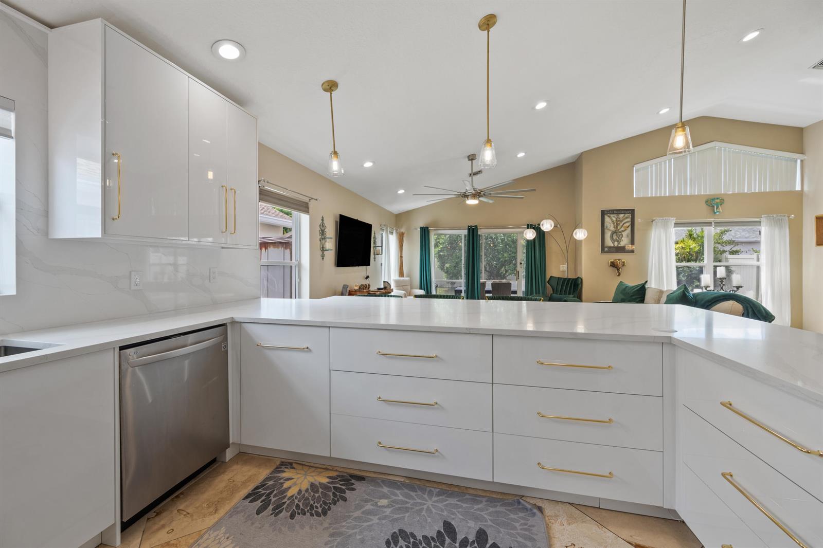 A modern kitchen features white cabinets, gold hardware, and a large quartz island countertop — 1097 Aviary Road, Wellington FL 33414, WELLINGTON, FL