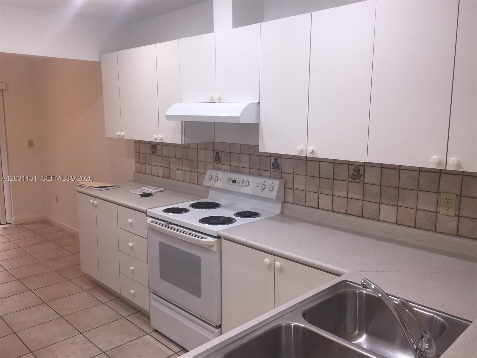 A kitchen features white cabinets, a white electric stove, and a stainless steel sink — 11449 SW 84 LN # 0, Miami FL 33173, MIAMI, FL