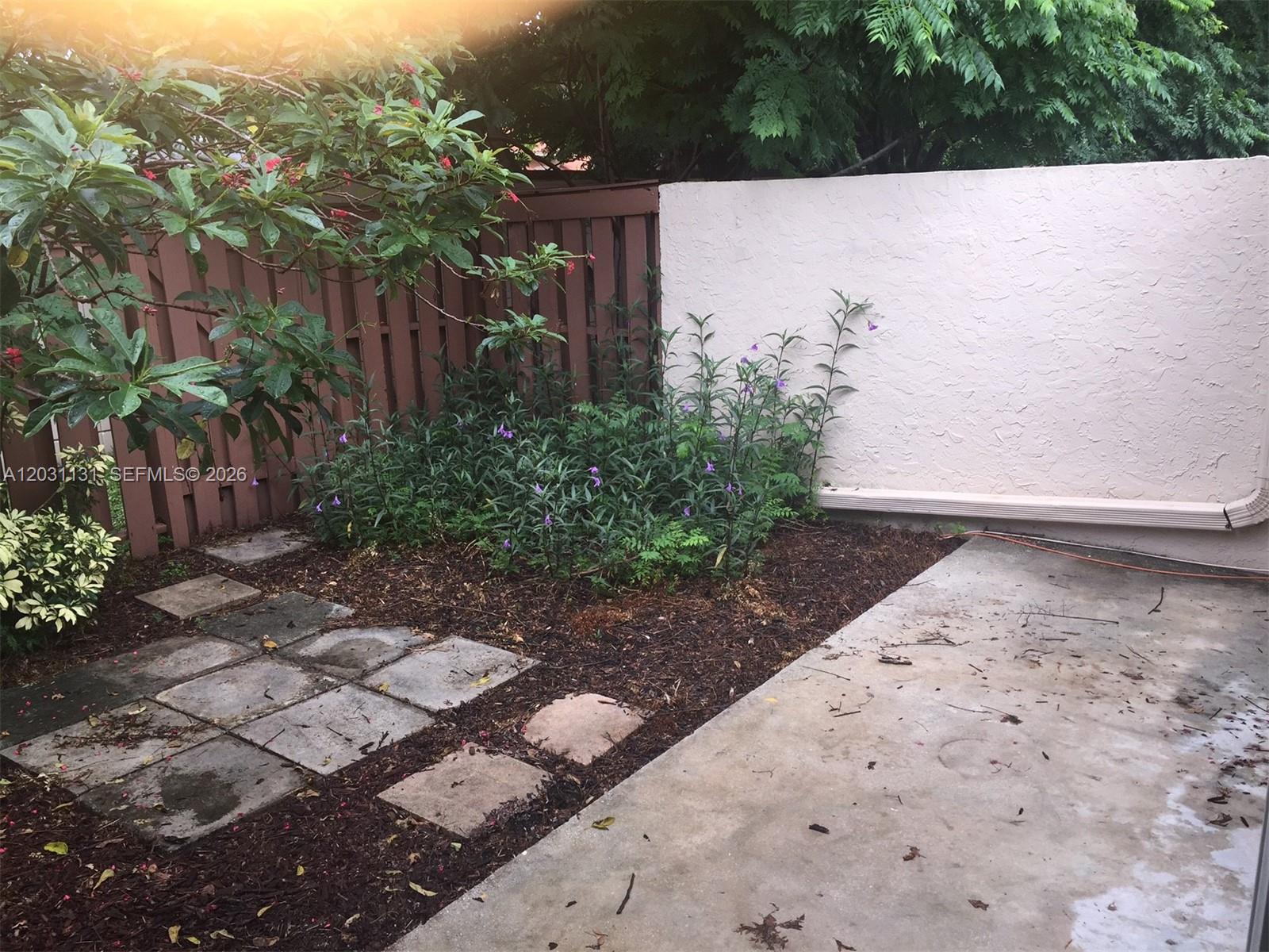 A small backyard features a concrete patio, stone pavers, a garden bed, and a privacy fence — 11449 SW 84 LN # 0, Miami FL 33173, MIAMI, FL