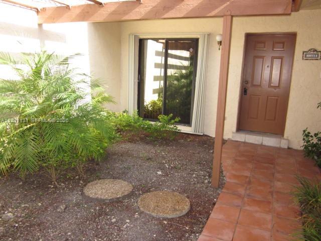 A brown front door and sliding glass door are visible next to a small garden — 11449 SW 84 LN # 0, Miami FL 33173, MIAMI, FL