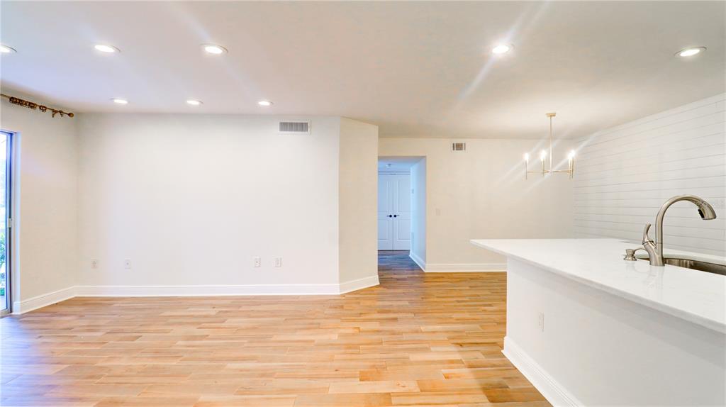 An open-concept room features light wood flooring, white walls, recessed lighting, and a kitchen island — 9481 HIGHLAND OAK DRIVE UNIT 1001, TAMPA, FL